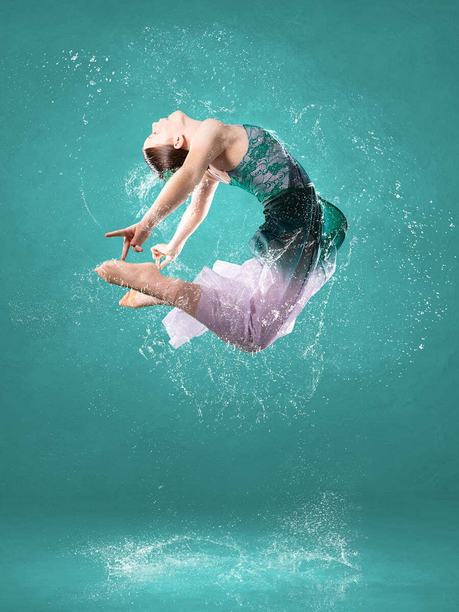 Contemporary dancer jumping in a photography studio with water splashes using digital art