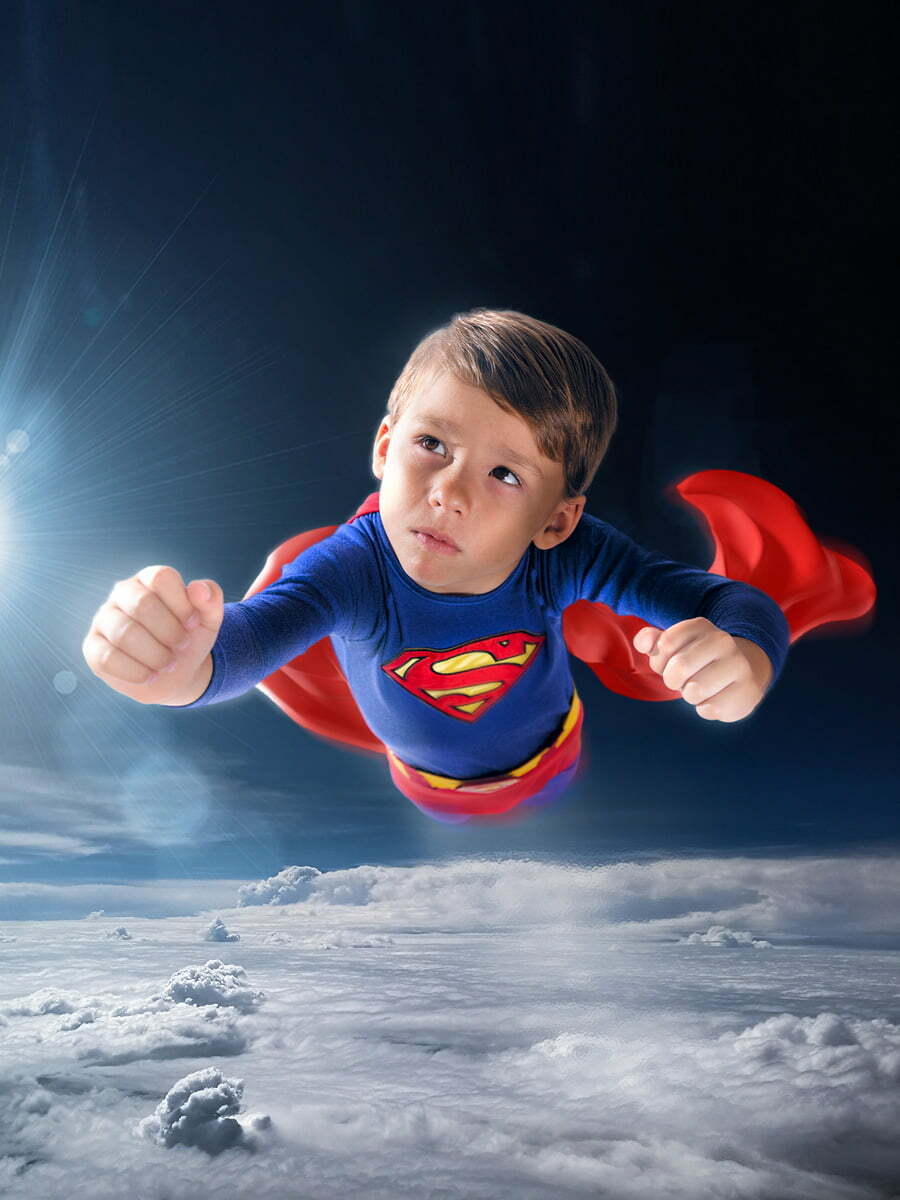Little boy in Superman costume flying in the sky using digital compositing