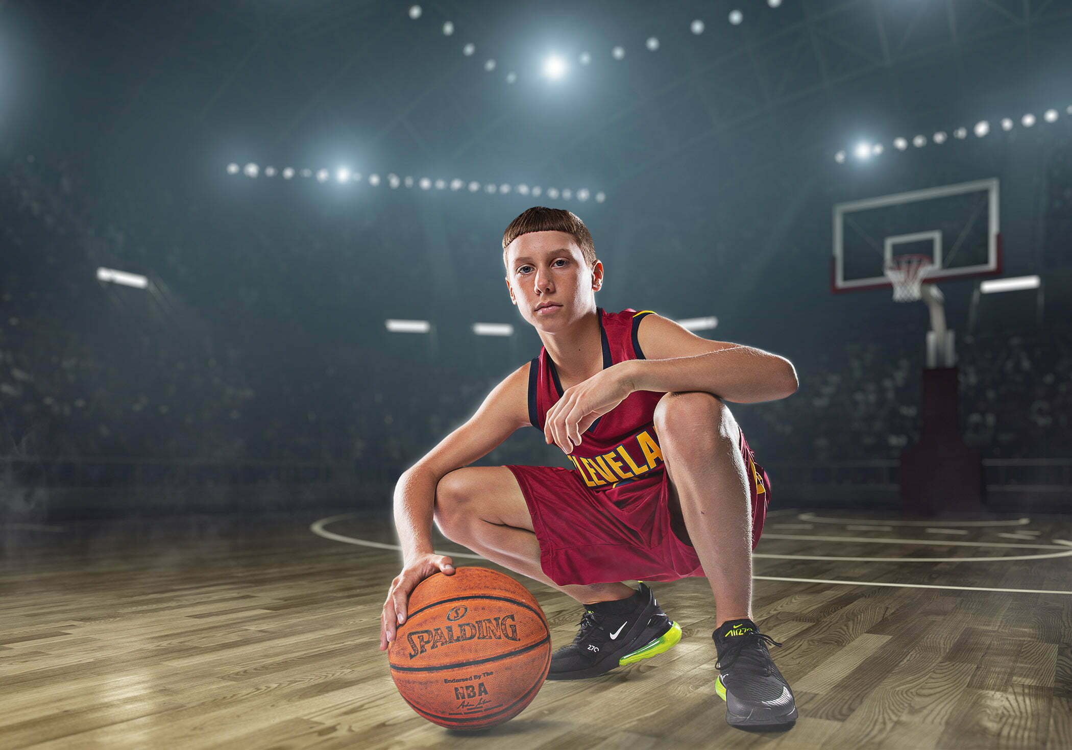 Teenage boy posing for a basketball sports portrait in a studio composited onto a digital stadium background