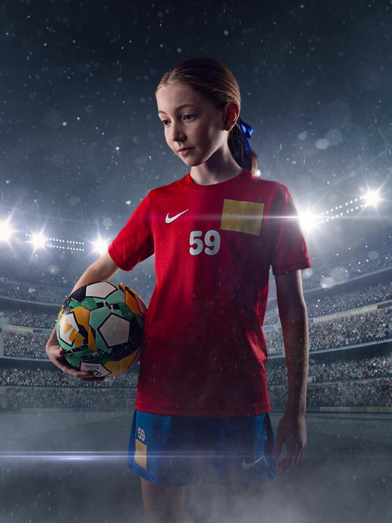 Portrait of a young girl soccer player, backlit with studio lighting holding a soccer ball.
